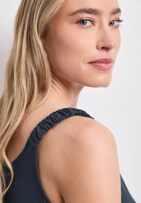 Knielanges Kleid mit gerafften Trägern shadowed navy Seitliche Nahaufnahme einer Frau mit langen blonden Haaren und schwarzem, gerafftem Träger-Top.