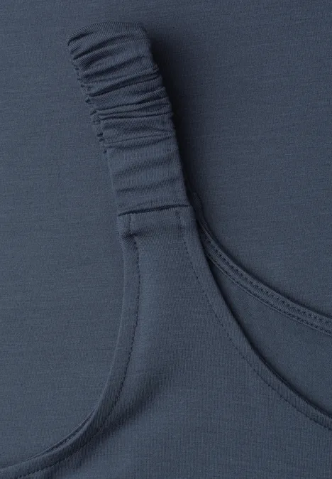 Nahe Aufnahme eines dunkelblauen BH-Trägers mit elastischem Detail auf einem Textilstoff.