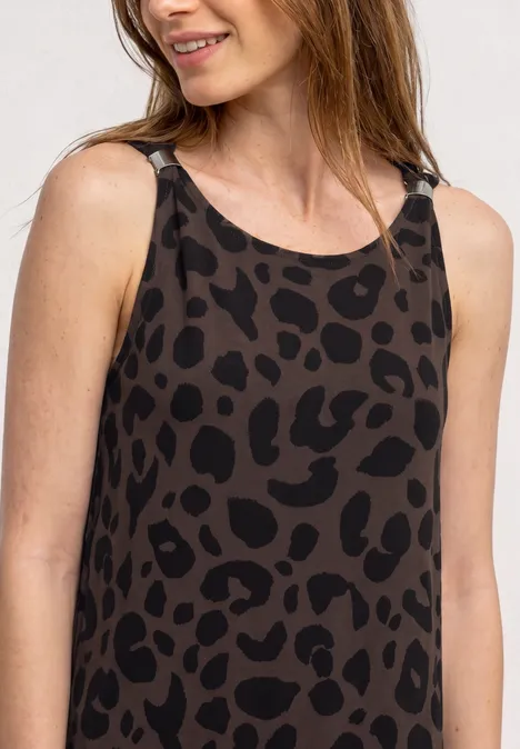 Frau mit braun-schwarzem Leoparden-Print-Top, lächelt seitlich.