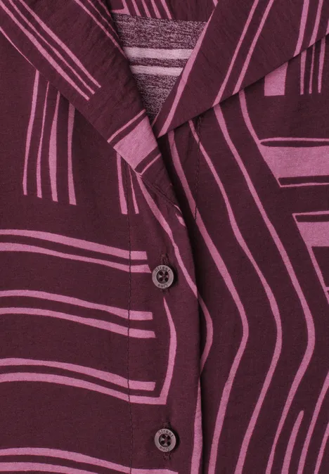 Nahaufnahme eines lila-gemusterten Blazers mit grafischen Linien und zwei sichtbaren Knöpfen.