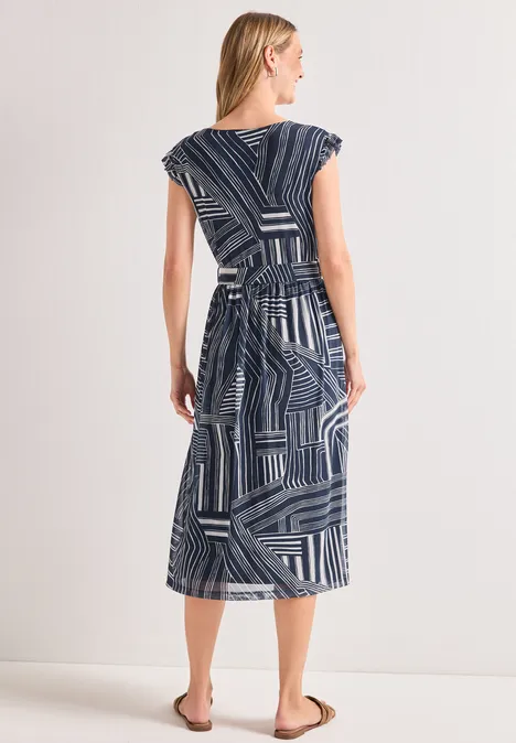 Frau im geometrisch gemusterten Midi-Kleid mit Gürtel, Rückenansicht