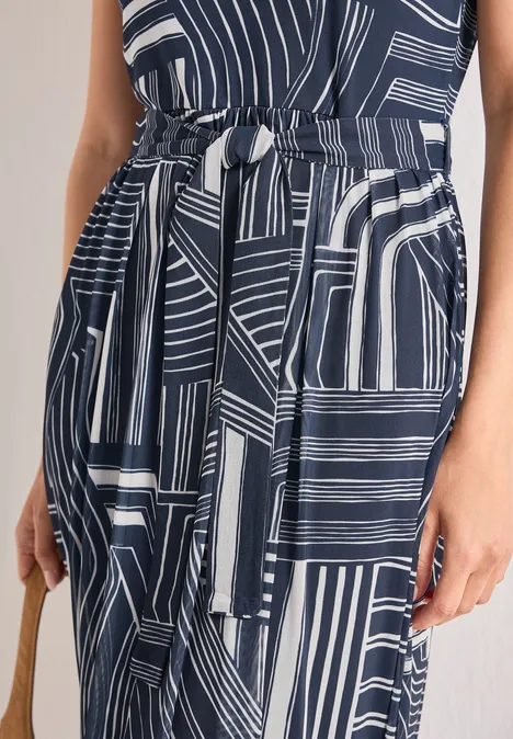 Nahaufnahme eines dunkelblauen Kleides mit weißen geometrischen Streifen, Taillengürtel und Handtasche.