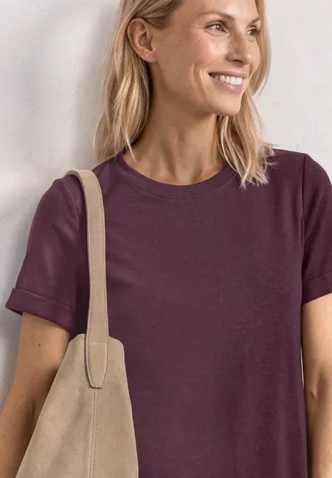 Midijurk met ribbelstructuur en ronde hals rustic rouge Vrouw met blond haar draagt een paarse t-shirt en een beige tas.