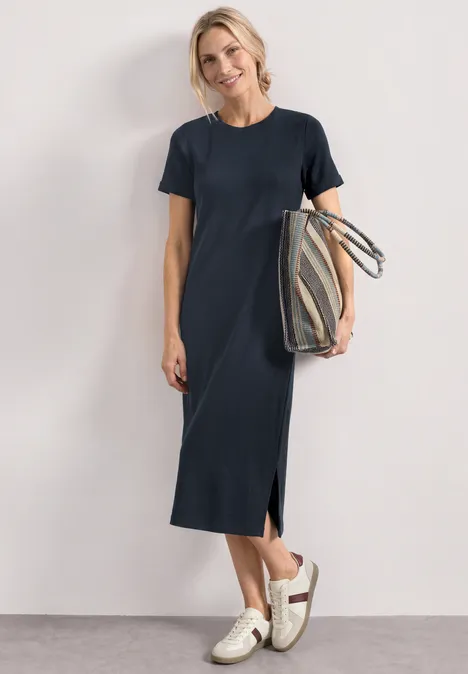 Midikleid in Rippstruktur mit Rundhals darkest blue Frau in schlichtem navy Midi-Kleid mit Seitenschlitz und Taschen, kombiniert mit weißen Sneakern und Streifentasche.