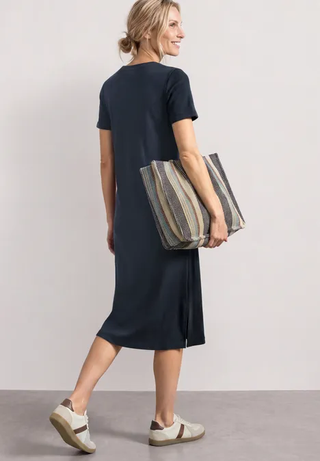 Midikleid in Rippstruktur mit Rundhals darkest blue Frau in dunkelblauem Midikleid trägt gestreifte Tasche und Sneakers, schlendert auf hellem Boden.