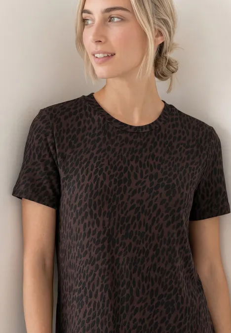 Midi-jurk met grafisch patroon molten earth Vrouw met blond opgestoken haar draagt een kort mouw T-shirt met bruin-zwart luipaardprint voor een lichte achtergrond.