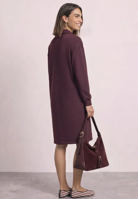 Robe en molleton arrivant aux genoux, avec fermeture éclair rustic rouge Une femme porte une robe violette tombant aux genoux, ample, et tient un sac assorti.