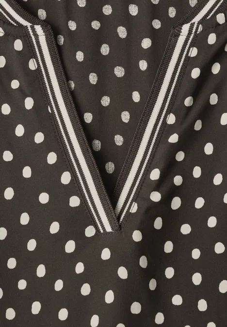 Midikleid mit Split Neck und Print black coffee Nahaufnahme eines schwarzen Stoffes mit weißen Punkten und einem V-förmigen Ausschnitt mit gestreiftem Detail.