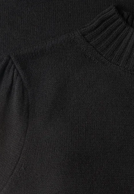 Nahaufnahme eines schwarzen Strickpullovers mit hohem Kragen.