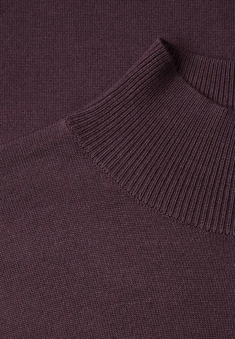 Nahaufnahme eines dunkelvioletten, gestrickten Rollkragenpullovers.
