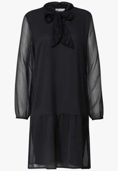 Schwarzes, knielanges Chiffonkleid mit transparenten Ärmeln, Rüschen am Saum und Schleifenkragen.