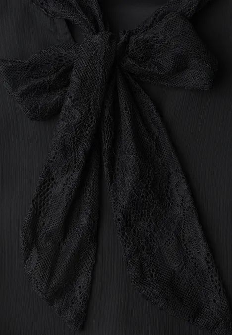 Schwarze Spitzen-Schleife an einem Kleidungsstück.