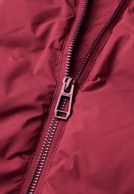 Kort jasje met gelijmde stiksels vintage red Close-up van een rode ritssluiting op rood textiel.