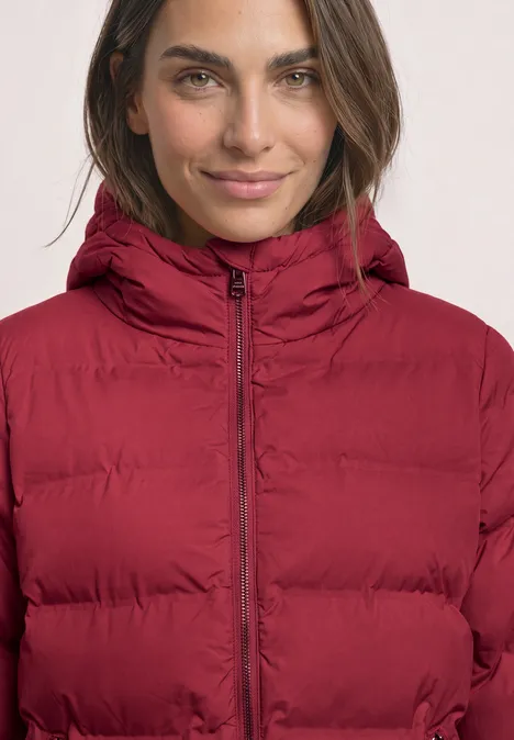 Kort jasje met gelijmde stiksels vintage red Vrouw in donkerrode gewatteerde jas met capuchon, recht van voren, lichte glimlach