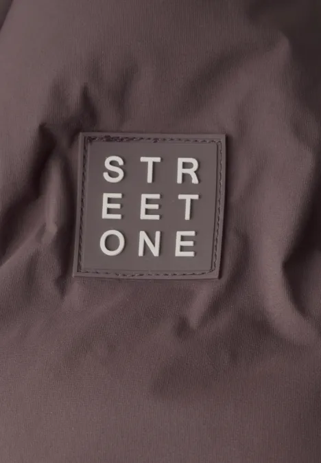 Étiquette textile carrée marron avec l’inscription blanche "STREET ONE" cousue sur le tissu.