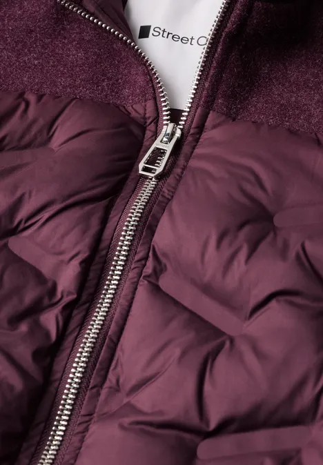 Naheinstellung einer bordeauxfarbenen Steppjacke mit Reißverschluss und Fleece-Kragen.