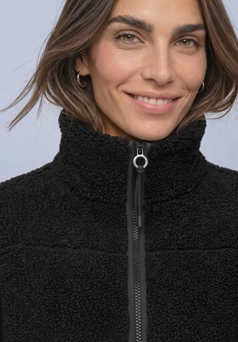 Nahaufnahme einer lächelnden Frau in schwarzer Teddy-Fleecejacke mit Reißverschluss