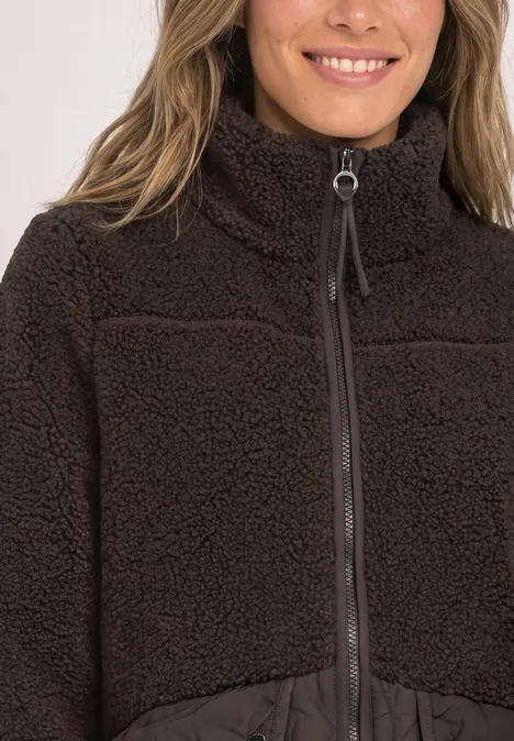 Nahaufnahme einer Person in brauner Fleecejacke mit Reißverschluss und hohem Stehkragen.
