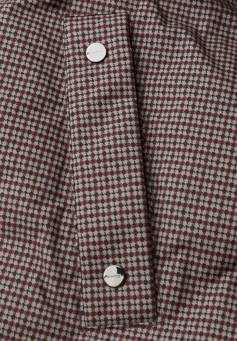 Nahaufnahme eines rot-grau karierten Stoffes mit weißen Knöpfen an einer Knopfleiste.