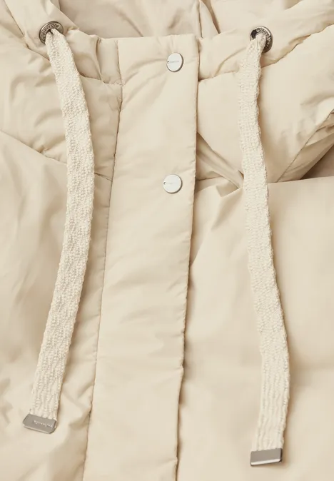 Beige gesteppte Jacke mit dicker Kordelzug an der Kapuze und silbernen Druckknöpfen.