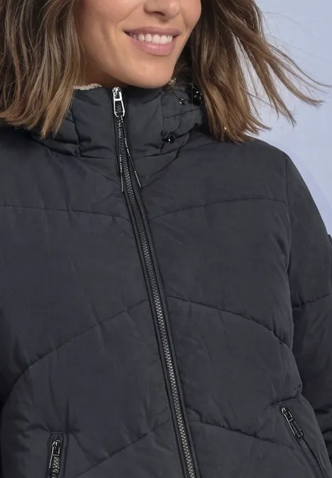 Frau in schwarzer gesteppter Jacke mit Reißverschluss, lächelnd