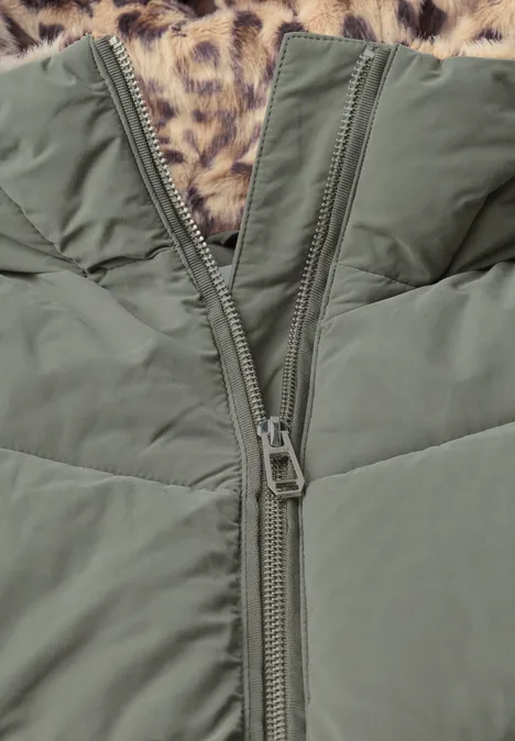 Grüne Steppjacke mit offenem Zwei-Wege-Reißverschluss auf Leopardenfell-Hintergrund.