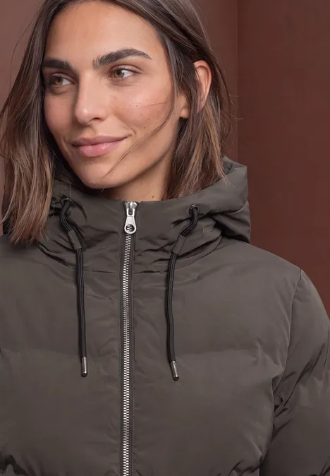 Pufferjacke mit Kapuze auburn brown Nahaufnahme einer Frau in brauner Steppjacke mit Kapuze, Reißverschluss und Kordelzügen.