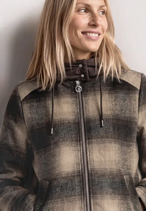 Veste contenant de la laine, avec capuche amovible auburn brown Fröhliche Frau mit blondem Haar trägt karierten Mantel mit Kapuze und lächelt seitlich.