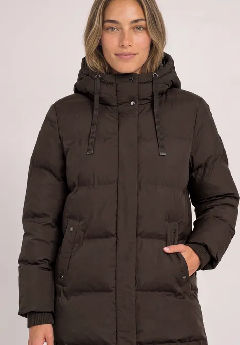 Lange Jacke mit Kapuze und Steppmuster auburn brown Frau trägt eine braune, gesteppte Kapuzenjacke, Hand in der rechten Reißverschlusstasche.