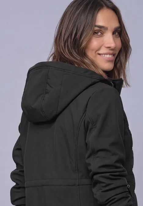 Veste softshell à capuche avec détails matelassés Black Eine Frau in schwarzem Kapuzenpulli dreht sich lächelnd zur Kamera.