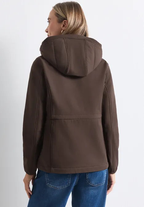 Frau trägt braune Softshell-Jacke mit Kapuze, Ansicht von hinten.