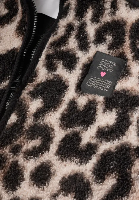 Lange Teddy-Jacke mit Stehkragen Black Nahaufnahme eines flauschigen Leopardenmusters mit Reißverschluss und einem 'Just Be Kind'-Patch.