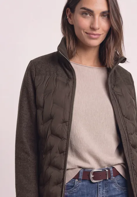 Strukturmix Jacke mit geklebter Steppung auburn brown Frau in olivgrüner Steppjacke mit beigem Pullover und braunem Gürtel.