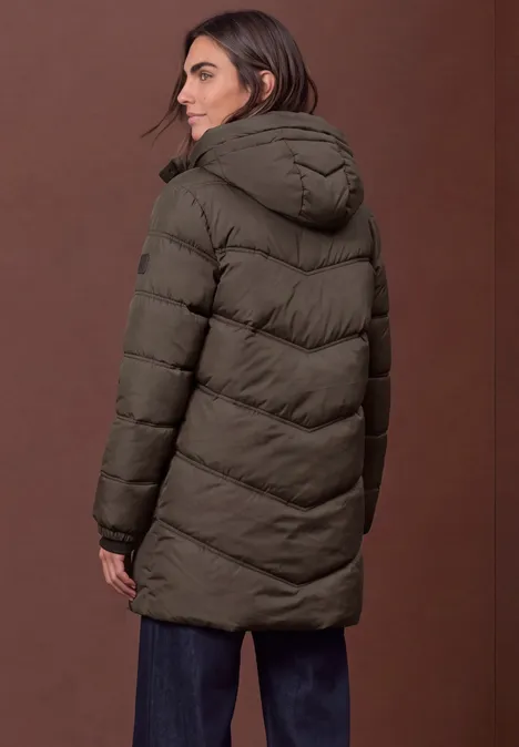 Lange Pufferjacke mit Kapuze auburn brown Frau in dunkelgrüner, taillierter Steppjacke mit Kapuze, seitliche Rückenansicht vor braunem Hintergrund