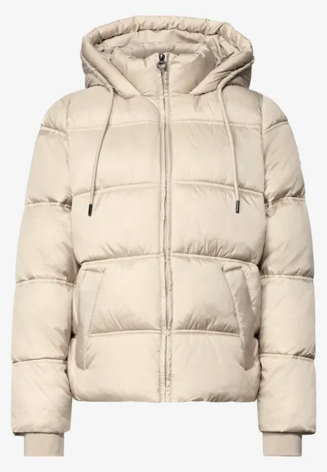 Beige Steppjacke mit Kapuze und Reißverschluss, gepolstert und wattiert.