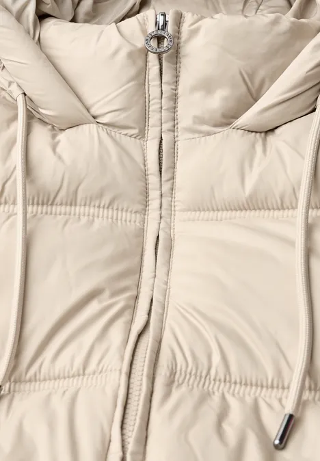 Helle Daunenjacke in Creme mit Reißverschluss, Ring-Zipper und Kordelzug am Kapuzenbereich.
