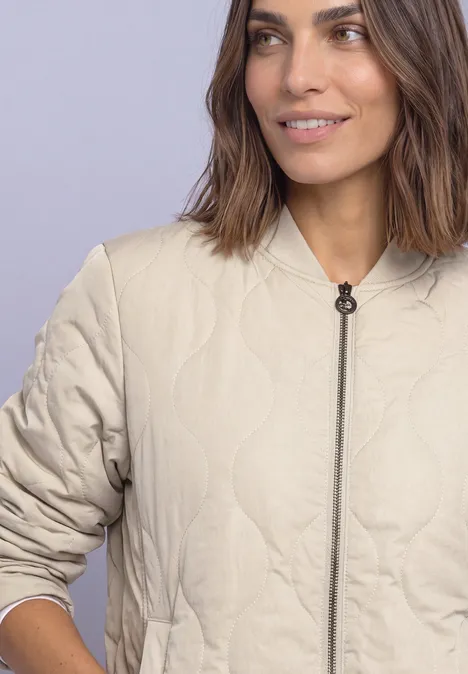 Blouson met doorgestikt patroon en ritssluiting barley beige Vrouw draagt een beige doorgestikte jas met rits en ronde hals, lichte achtergrond.