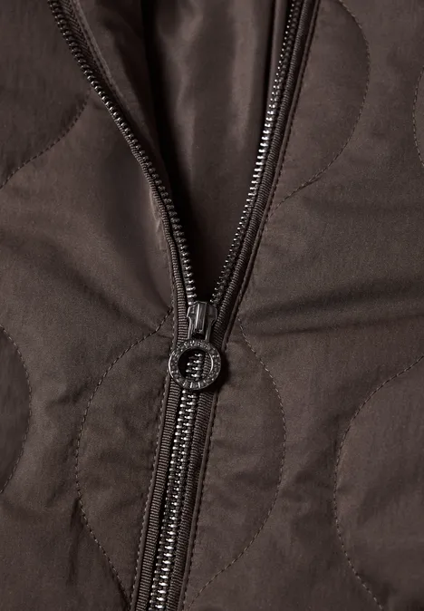 Nahaufnahme einer braunen, gesteppten Jacke mit teilweise geöffnetem Reißverschluss.