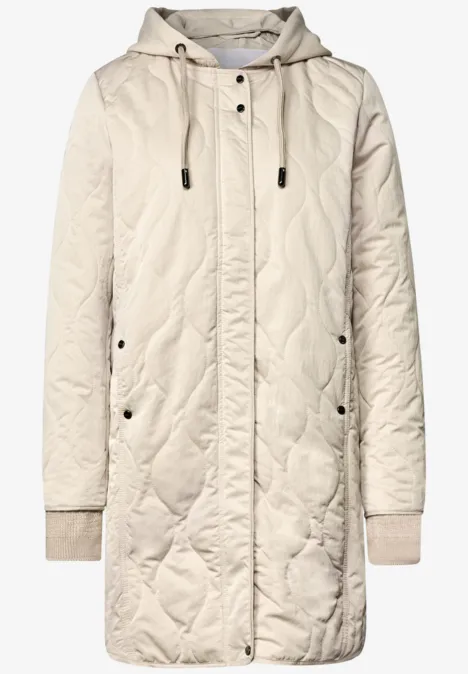 Beige gesteppte Kapuzenjacke mit Reißverschluss, Druckknöpfen, zwei Taschen und Rippbündchen.