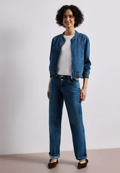 Denim-look blouson met ritssluiting Medium Blue washed Persoon met blauwe spijkerbroek, wit T-shirt, blauw jasje en zwarte schoenen voor een lichte achtergrond.