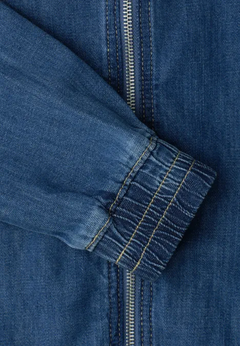 Denim-look blouson met ritssluiting Medium Blue washed Close-up van een blauwe spijkerjasmouw met ritssluiting en elastische manchetrand.