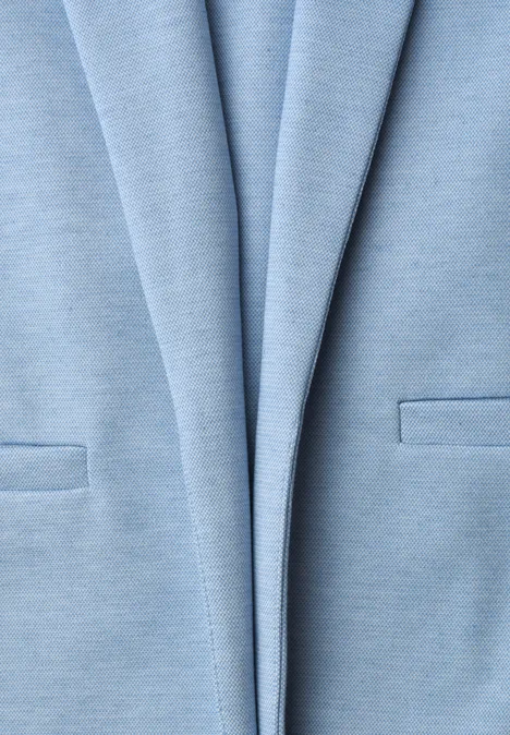 Gros plan d'un blazer bleu clair avec revers et poches plaquées.