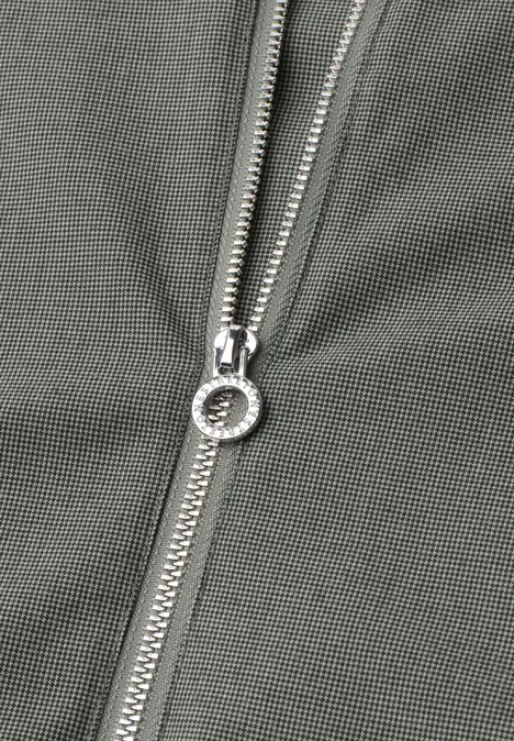 Close-up van een zilverkleurige ritssluiting op olijfgroene stof.