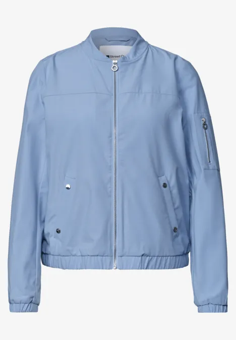 Lichtblauwe bomberjas van licht materiaal, rits voor, geribde boorden en zakken.