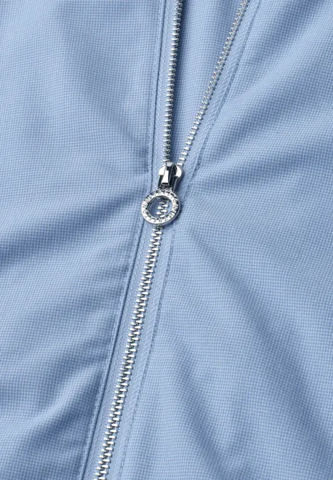 Close-up van een zilveren rits op lichtblauwe stof