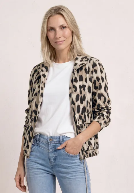 Person mit weißem T-Shirt, blauer Jeans und Leopardenjacke.