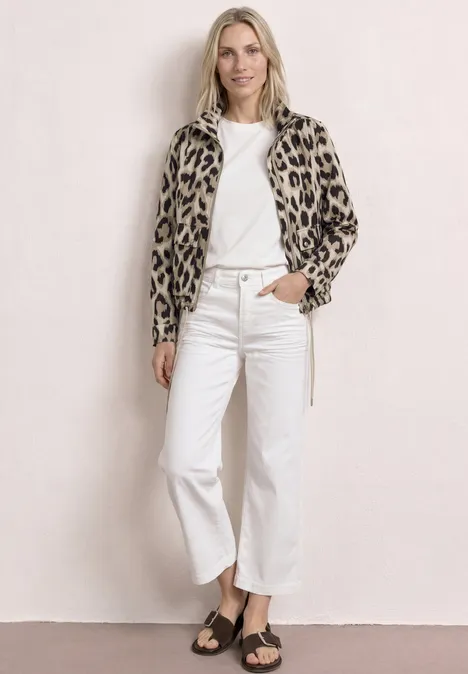 Frau trägt Leopardenjacke, weißes T-Shirt, weiße Culotte-Jeans und schwarze Sandalen.