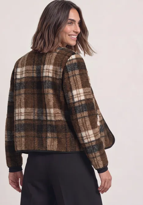 Teddy-Jacke mit Rundhals und Print Obsidian Blue Eine Frau blickt über die Schulter und trägt eine braun karierte Jacke mit dunkler Hose.