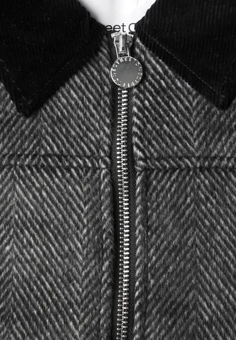 Nahaufnahme einer grauen Fischgrät-Jacke mit schwarzem Kragen und Reißverschluss.