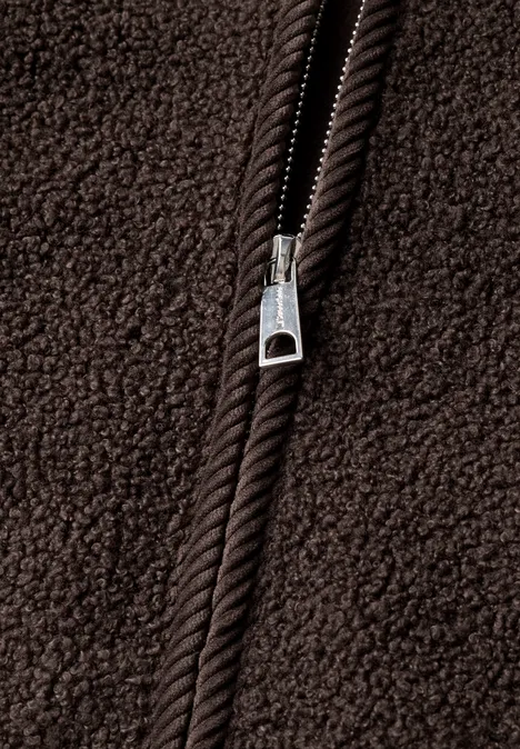 Nahaufnahme eines braunen Fleece-Stücks mit sichtbarem Metallreißverschluss.